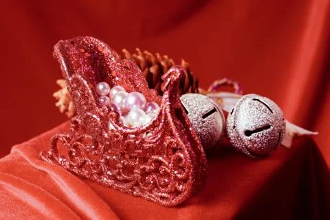 Small toy sleigh with multi-colored pearls on a red background. Stock Photos