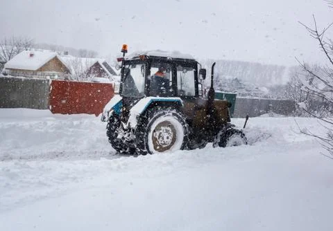 A small tractor clears the road from snow Stock Photos