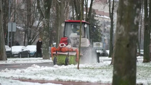 A small tractor clears snow from sidewalks in the city on a winter day. Stock Footage 147293601