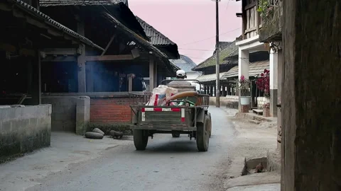 A small tractor drives through a small Dai village in China’s Yunnan Province.  Stock Footage 158822321