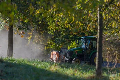 Small tractor of the municipality with front mounted leaf blower device drivi Stock Photos