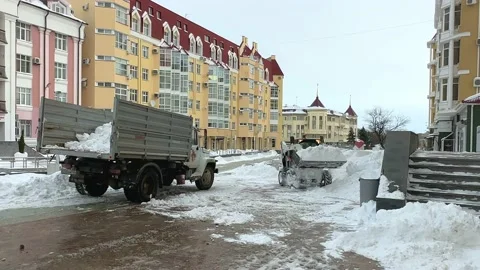 A small tractor - snow plow, collects with a bucket and clears snow drifts  Stock Footage 233118451