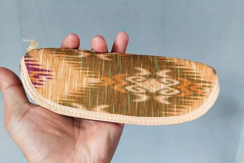 A small traditional patterned fabric pouch held in hand, featuring a zipper.. Stock Photos