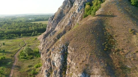A small trail leads to a large mountain range whose slopes are overgrown with Stock Footage 158811608