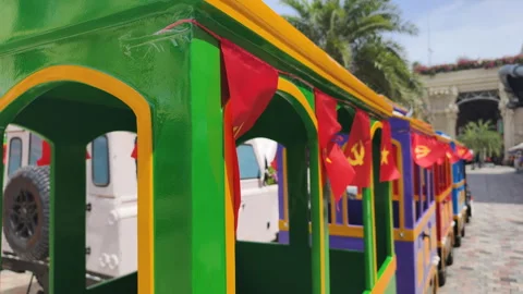 A small train ride decorated with Vietnamese flags featuring hammer and sickle. Stock Footage 317806385