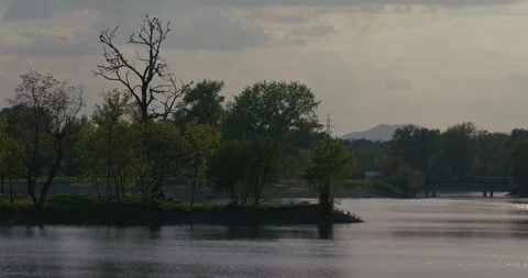 Small tree-covered island in lake with bridge in background 스톡 동영상 332948686