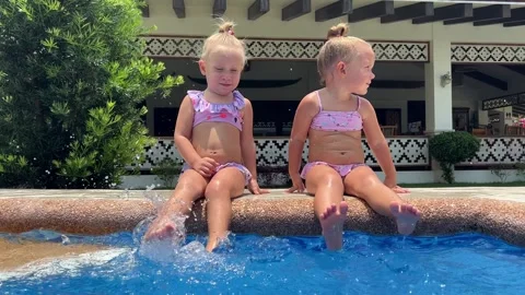 Small triplets sisters playing in the pool in swimsuits 库存影片 244007898