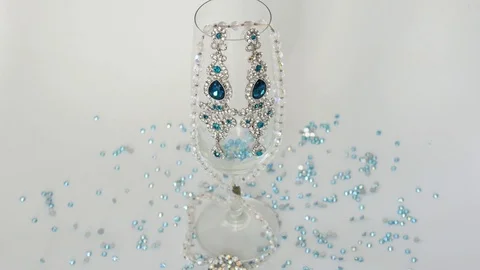 Small Turquoise Rhinestones Pour in Empty Glass of Champagne With Chic Earrings Stock Footage 122805007