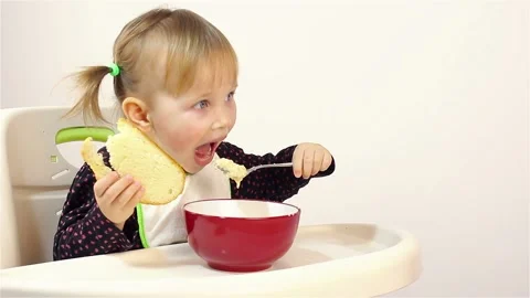 A small two-year-old girl eats porridge. Stock Footage 87575615