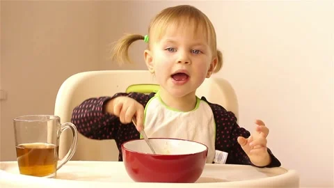 A small two-year-old girl eats porridge. Stock Footage 87613060