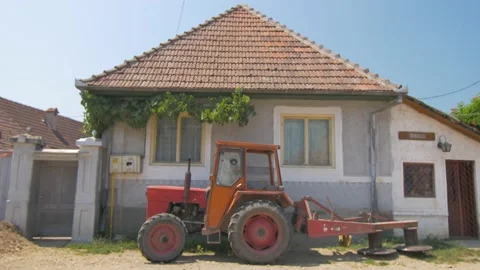 Small typical house with an old tractor in a small village in Romania Stock Footage 231266736