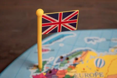 Small UK flag pin placed on a colorful world map Stock Photos