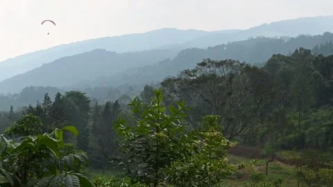 A small unidentified paraglider soars above a breathtaking mountain landscape. Video stock 342225324
