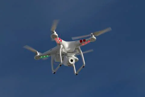 Small unmanned helicopter with a camera floating in the blue sky Stock Photos