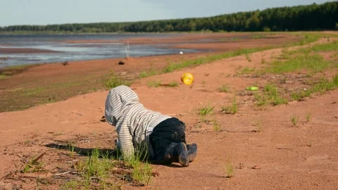 Small unrecognizable kid exploring world on sea beach. Baby crawls on nature Stock Footage 131609683