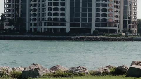 Small utility boat moving across a calm urban waterway with modern wat Stock Footage 326863349