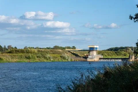 Small water dam regulating the flow of a wide river surrounded Foto stock