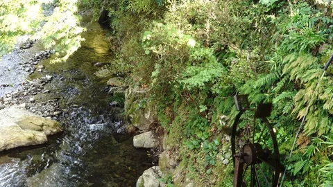 Small water mill perched on a steep river bank, 4K, handheld Stock Footage 97037249