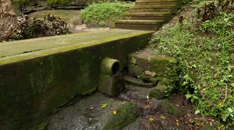 Small water outlet and tiny stream trickle through, mossy concrete way Stock Footage 52080036