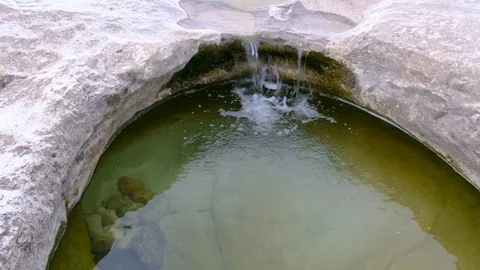 Small water stream flowing into natural stone pool Video stock 103628655