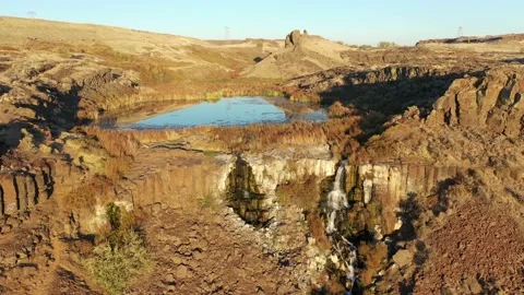 Small waterfall at Ancient Lakes at sunset with high bluffs and cliffs Stock Footage 144137679