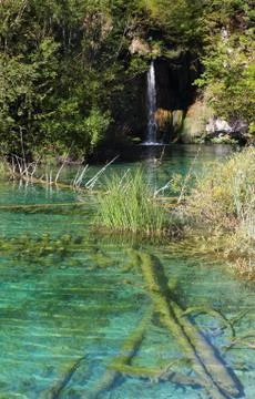 Small waterfall and an emerald colored lake Stock Photos