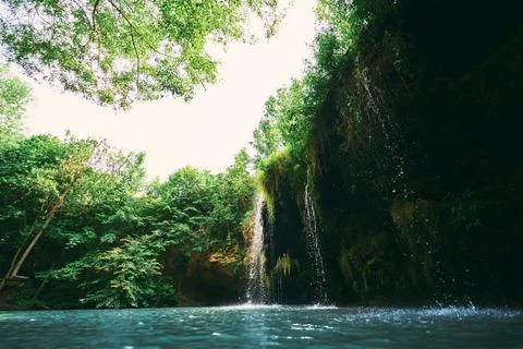 A small waterfall and a lake surrounded by trees in the summer. Wonderful lan Stock Photos