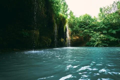 A small waterfall and a lake surrounded by trees in the summer. Wonderful lan Stock Photos