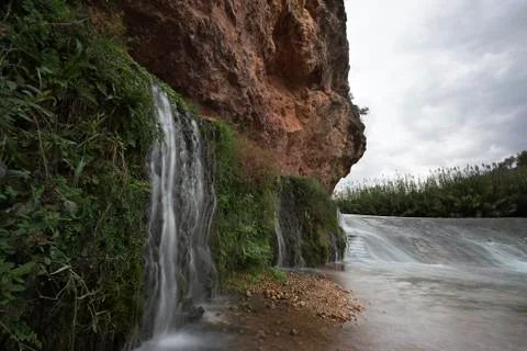 Small waterfall beside the river Stock Photos