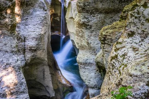 Small waterfall between white rocks with moss. Smooth water. Stock Photos