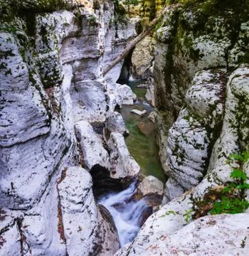 Small waterfall between white rocks with moss. Smooth water. Stock Photos
