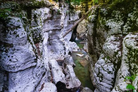 Small waterfall between white rocks with moss. Smooth water. Stock Photos