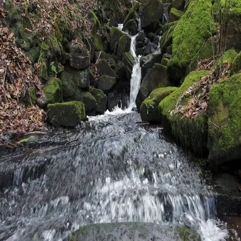 Small waterfall breaks out into wide stream of smooth flowing water Video stock 69519235