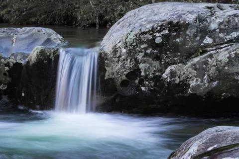 Small waterfall cascade between two large rocks Stock Photos