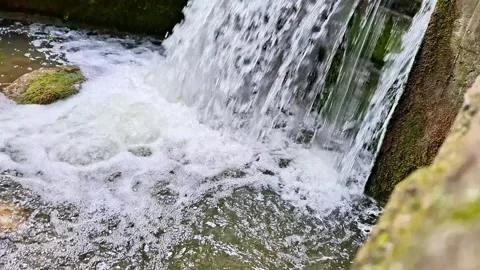 Small Waterfall Cascade Flowing Over Mossy Stone Structure Stock Footage 337528396