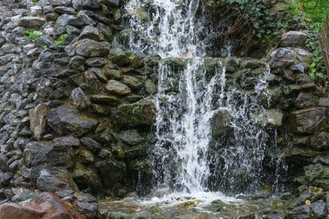 Small waterfall, cascade flowing over mossy boulders Stock Photos