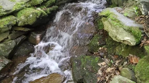 A small waterfall cascading between moss-coloured rocks 스톡 동영상 243036948