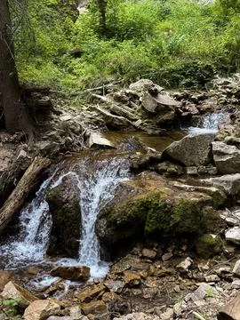 Small Waterfall Cascading Over Mossy Rocks in a Forest Stock Photos
