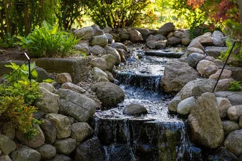 Small waterfall cascading over rocks and stones Stock-Fotos