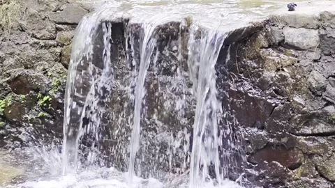 Small waterfall cascading over stone wall in clear natural stream Stock-Footage 347010514