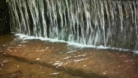 Small Waterfall Cascading into Shallow Pool Stock Footage 306439652