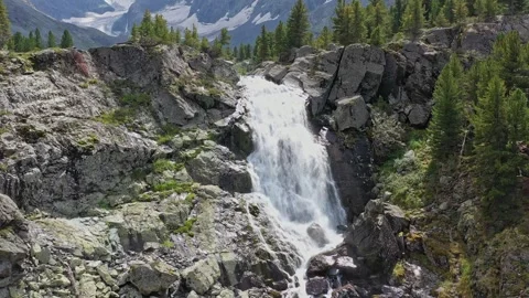 A small waterfall on a cliff with a forest on a sunny day. Stock Footage 264510757
