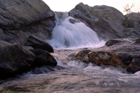 A small waterfall coming down the hill cutting the rocks Stock Photos