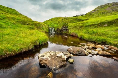 Small waterfall coming down from the mountain in an idyllic green landscape on Foto stock