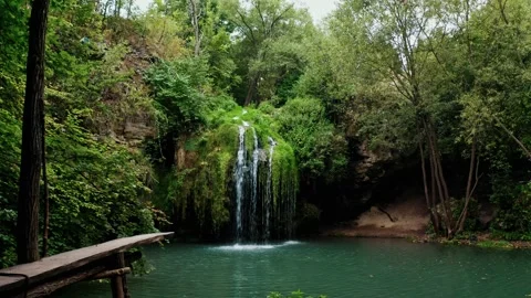 Small waterfall coming out of the forest falls to a small pond Stock Footage 195506379