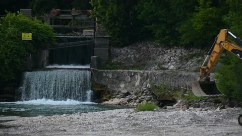 Small waterfall dam. Manmade structure. Yellow excavator hand and bucket Stock Footage 136233943