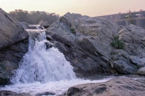 A small waterfall failing down between the rocks downhill Stock Photos