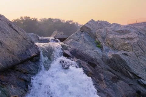 A small waterfall failing down between the rocks downhill Stock Photos
