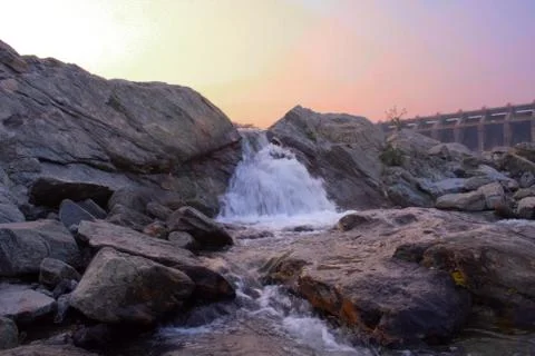 A small waterfall flowing between the rocks during sunset Stock Photos