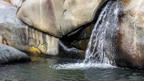 Small waterfall flowing cascade over rock formations into a pond Stock Photos